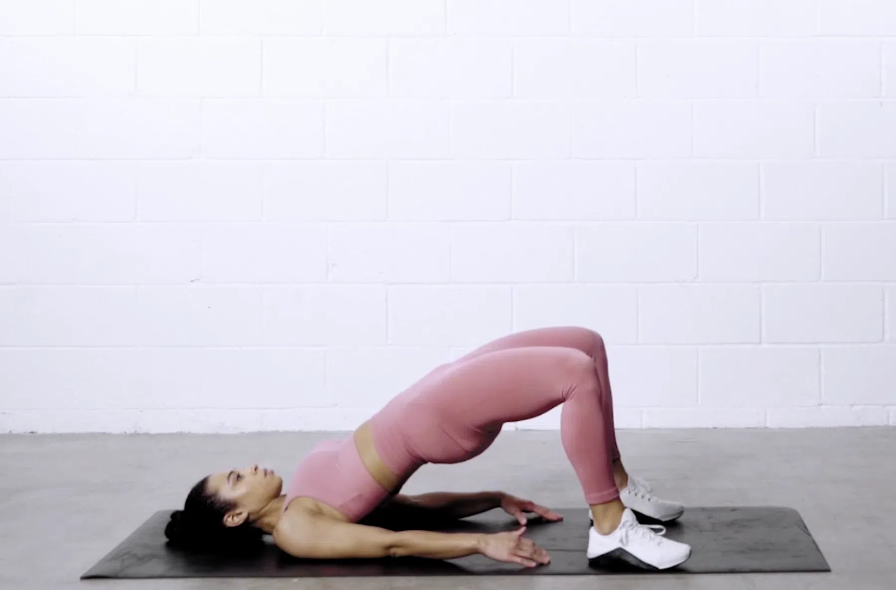 Vrouw doet de glute-bridge op een yogamatje.